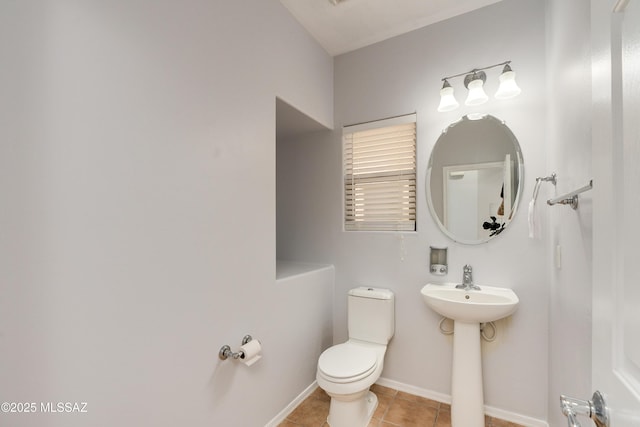 half bathroom with baseboards, toilet, and tile patterned floors