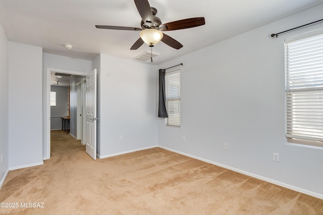 unfurnished room with a healthy amount of sunlight, baseboards, visible vents, and light colored carpet