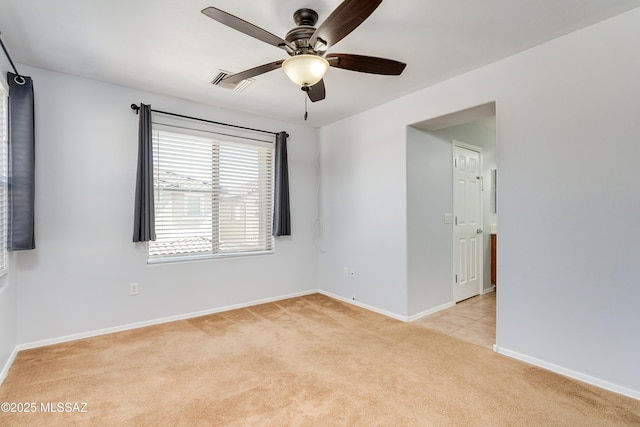 empty room featuring baseboards, ceiling fan, visible vents, and light colored carpet