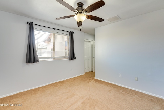 spare room with light colored carpet, a ceiling fan, baseboards, visible vents, and attic access