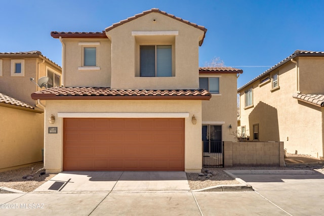 mediterranean / spanish house with a garage, fence, concrete driveway, and stucco siding