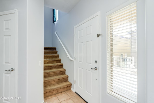 foyer entrance featuring light tile patterned floors and stairs