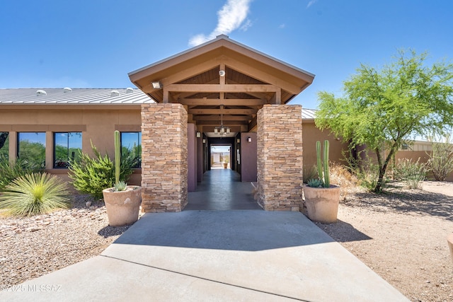 property entrance featuring metal roof, stone siding, a standing seam roof, and stucco siding