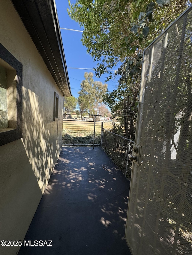 exterior space featuring a gate, fence, and stucco siding