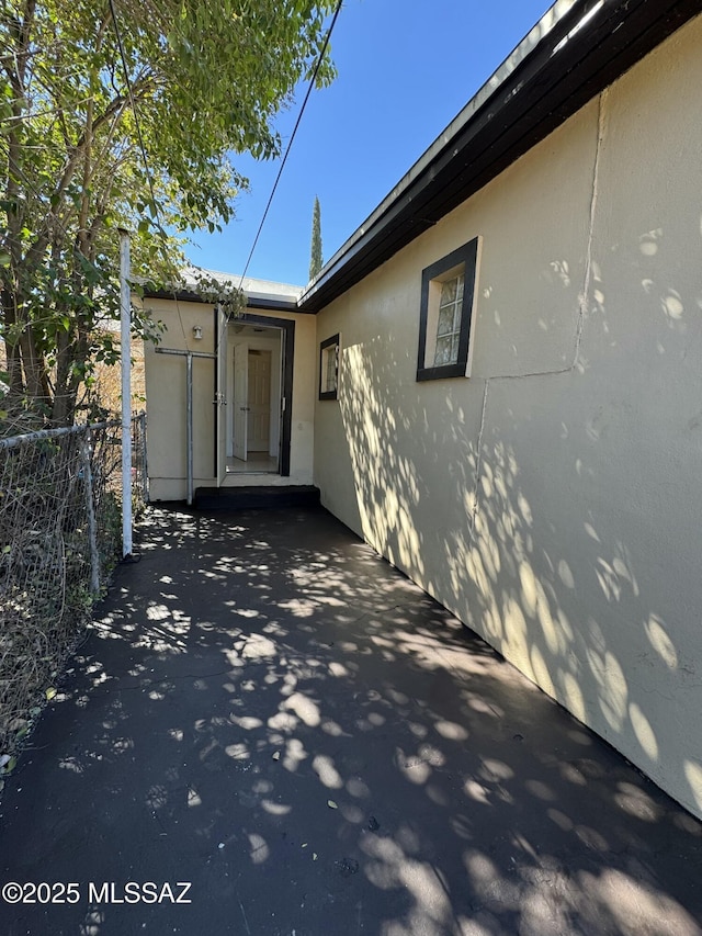 view of side of home featuring a patio, fence, and stucco siding