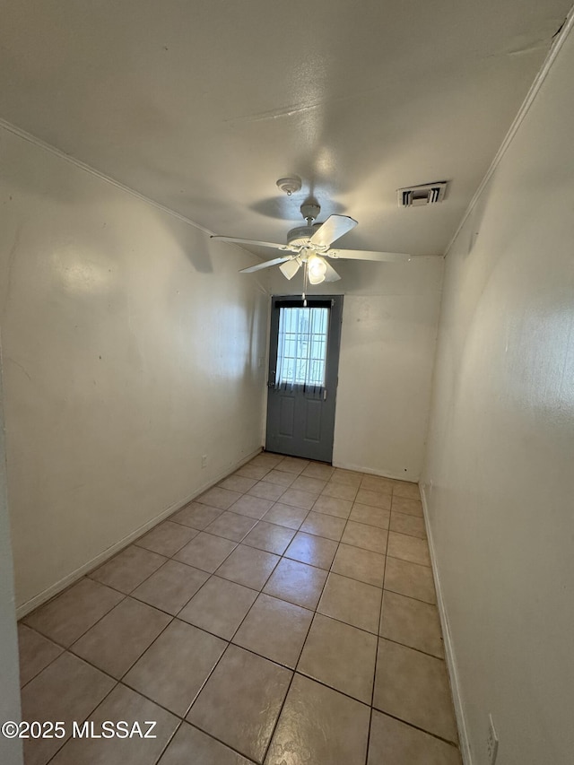 doorway featuring visible vents, ornamental molding, light tile patterned flooring, ceiling fan, and baseboards