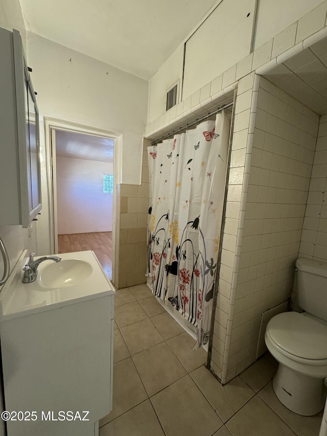 full bathroom featuring tile walls, visible vents, toilet, a shower with shower curtain, and tile patterned flooring