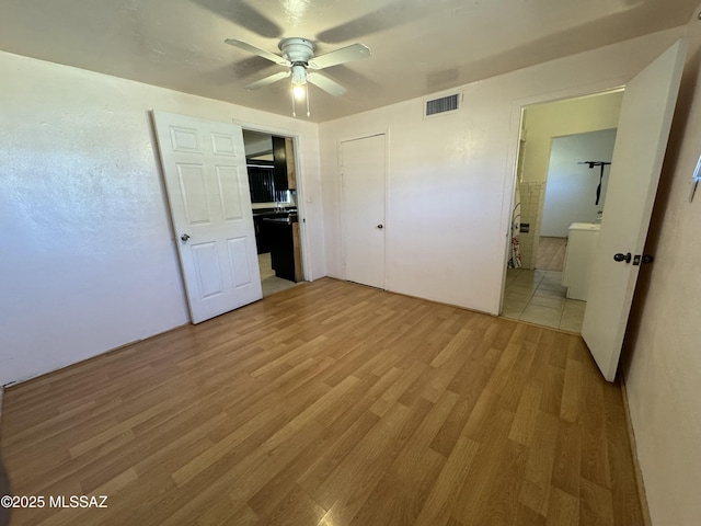 unfurnished bedroom with visible vents, ceiling fan, washer / clothes dryer, light wood-type flooring, and a closet