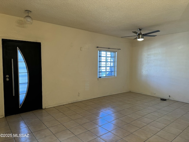 unfurnished room with ceiling fan, light tile patterned floors, and a textured ceiling