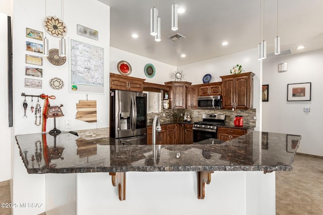 kitchen with a breakfast bar area, visible vents, appliances with stainless steel finishes, backsplash, and dark stone counters