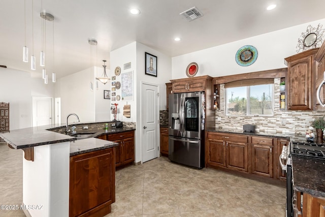 kitchen featuring tasteful backsplash, visible vents, a peninsula, stainless steel appliances, and a sink