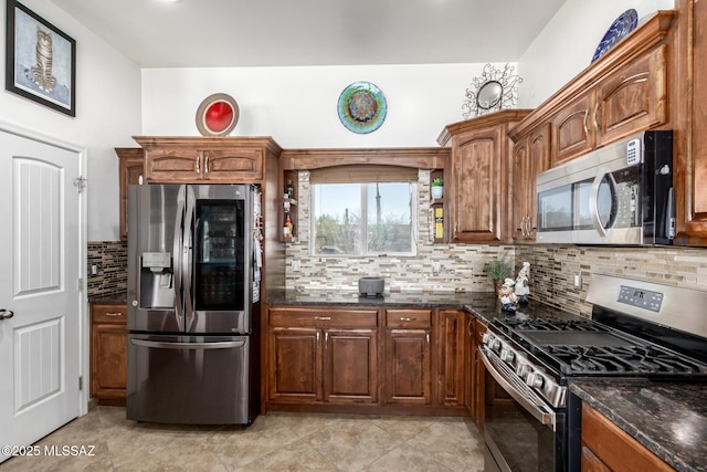 kitchen with stainless steel appliances, dark stone counters, brown cabinetry, and backsplash