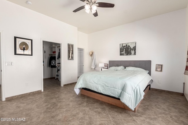 bedroom with ceiling fan, baseboards, a walk in closet, and a closet