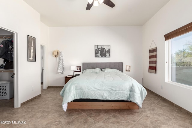 bedroom featuring ceiling fan, a walk in closet, and baseboards