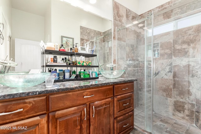 bathroom with a sink, a shower stall, and double vanity