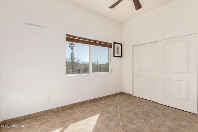 unfurnished bedroom featuring a ceiling fan, tile patterned flooring, baseboards, and a closet