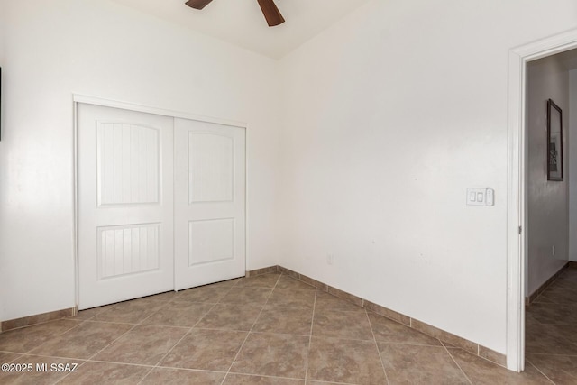 unfurnished bedroom featuring baseboards, ceiling fan, a closet, and tile patterned floors