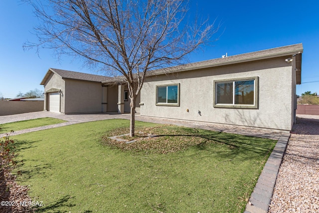 ranch-style home with a garage, a front yard, and stucco siding