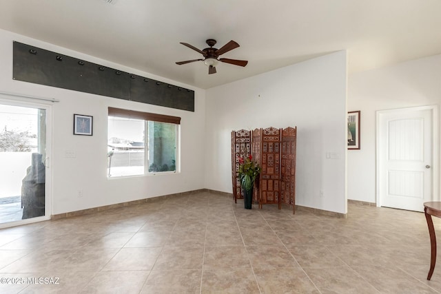 unfurnished room featuring a ceiling fan, baseboards, and light tile patterned floors