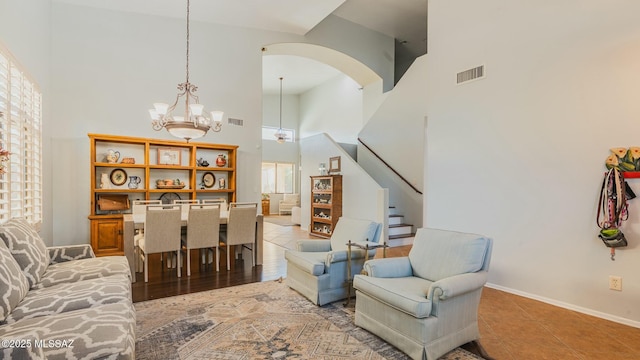 living area featuring visible vents, a towering ceiling, stairway, light tile patterned flooring, and baseboards