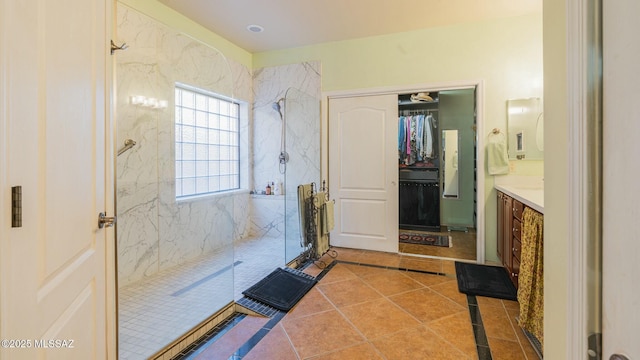 bathroom with a marble finish shower, a spacious closet, vanity, and tile patterned floors