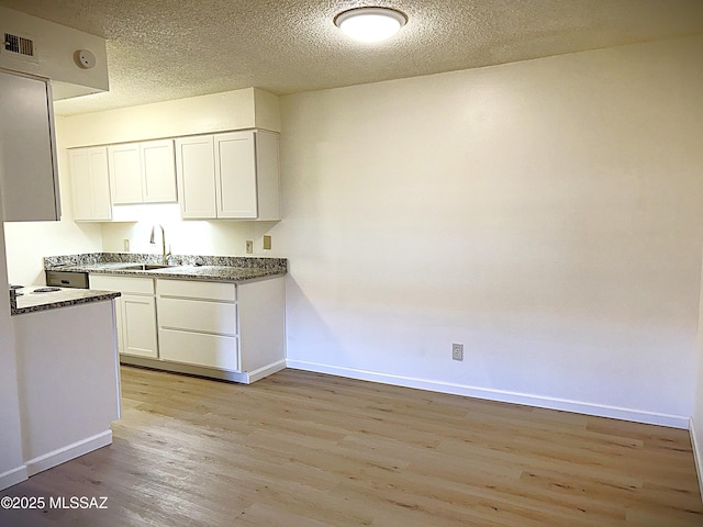 kitchen with light wood-style flooring, baseboards, white cabinets, and a textured ceiling