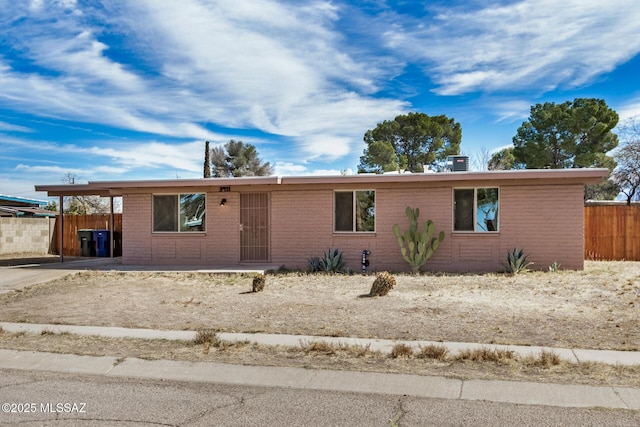 ranch-style house with driveway, fence, a carport, and brick siding