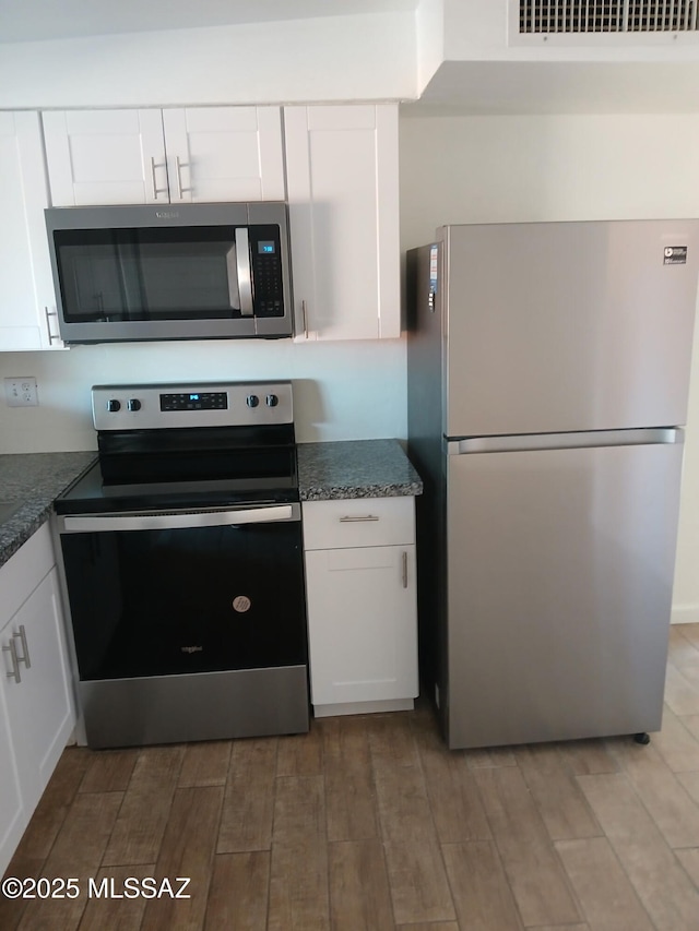 kitchen with visible vents, light wood-style flooring, white cabinets, and stainless steel appliances