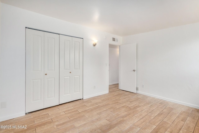 unfurnished bedroom with a closet, baseboards, visible vents, and light wood-type flooring