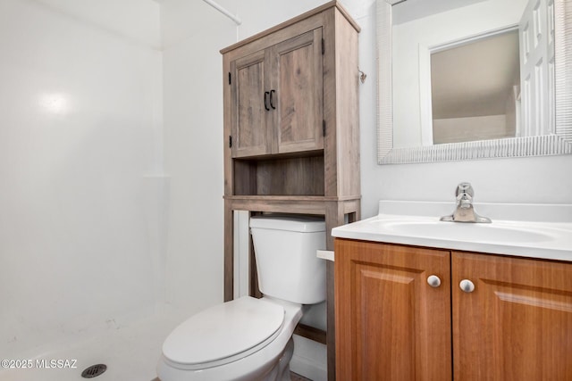 bathroom with vanity, a shower stall, and toilet