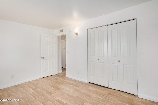 unfurnished bedroom featuring light wood-style floors, baseboards, a closet, and visible vents
