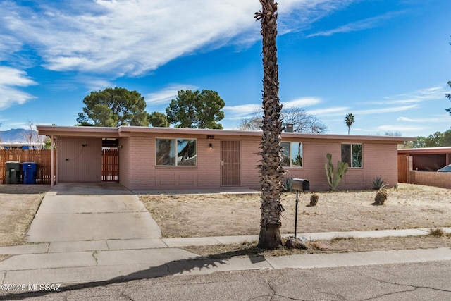 single story home featuring driveway, fence, an attached carport, and brick siding