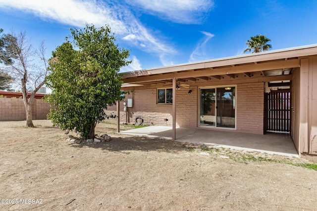 rear view of house with a patio, fence, and brick siding
