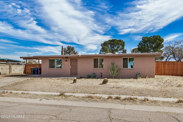 ranch-style home featuring a carport, concrete driveway, brick siding, and fence