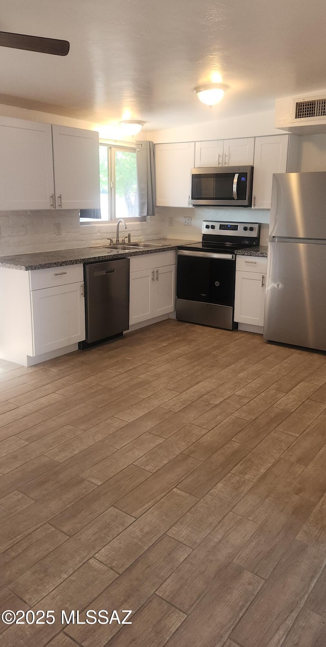 kitchen with white cabinets, stainless steel appliances, and tasteful backsplash