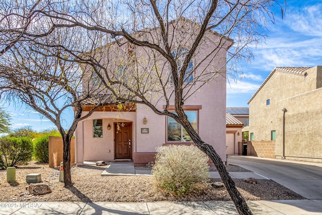 view of front of home with a tile roof, stucco siding, concrete driveway, an attached garage, and fence