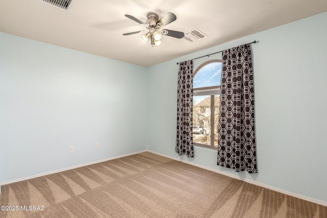 carpeted spare room featuring ceiling fan, visible vents, and baseboards