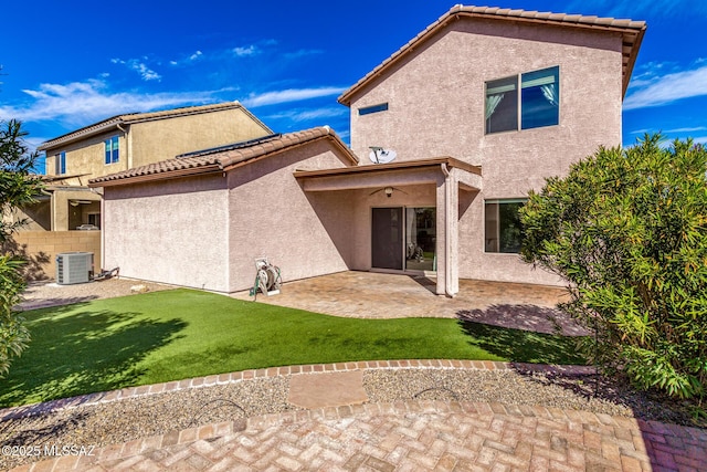 back of property featuring a lawn, a patio, a tile roof, cooling unit, and stucco siding