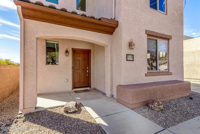 entrance to property with fence and stucco siding