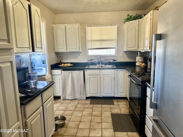 kitchen with black appliances, dark countertops, a sink, and white cabinetry