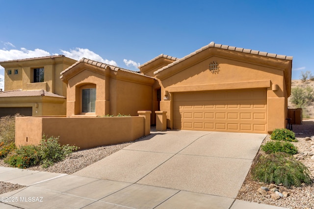 view of front of house with driveway, a tiled roof, an attached garage, a fenced front yard, and stucco siding