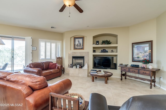 living area featuring visible vents, a fireplace, a ceiling fan, built in features, and tile patterned flooring