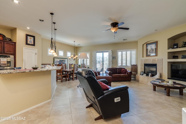 living area with recessed lighting, light tile patterned floors, ceiling fan with notable chandelier, built in shelves, and a fireplace