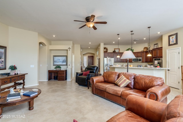 living room featuring arched walkways, baseboards, recessed lighting, and a ceiling fan