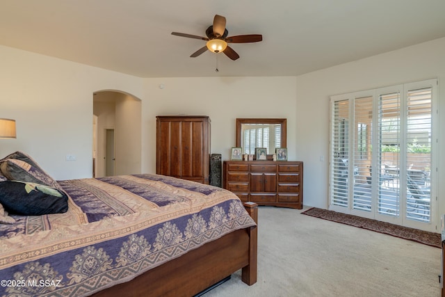 bedroom featuring carpet flooring, arched walkways, access to outside, and ceiling fan
