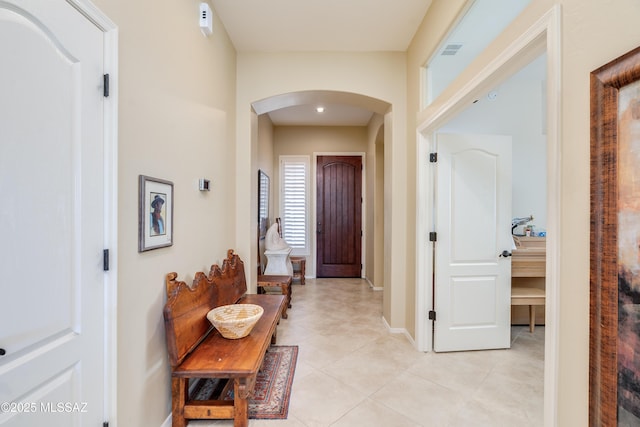 foyer entrance with baseboards, visible vents, arched walkways, and light tile patterned floors