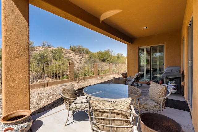 view of patio featuring a grill, outdoor dining area, and fence