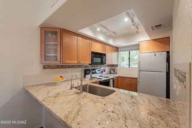 kitchen with a textured ceiling, light stone counters, white appliances, visible vents, and tasteful backsplash