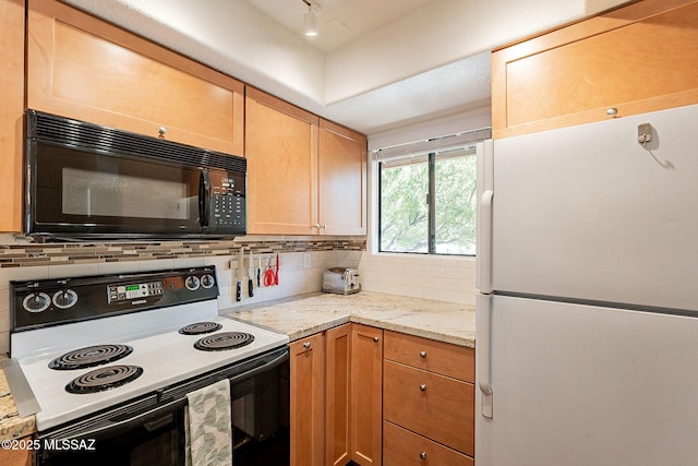 kitchen with range with electric stovetop, decorative backsplash, freestanding refrigerator, light stone countertops, and black microwave