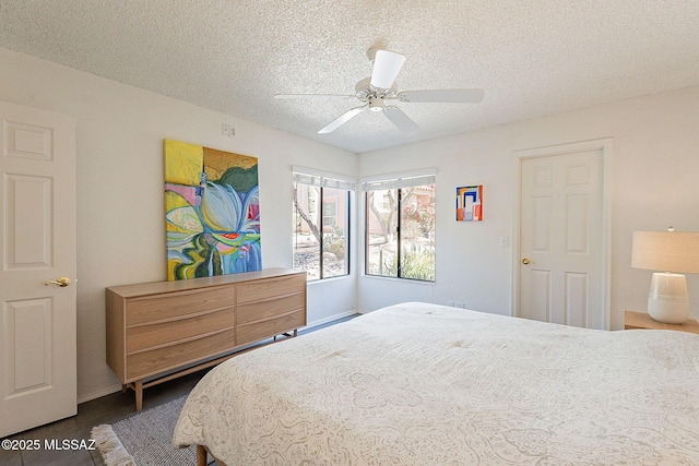 bedroom with a ceiling fan, dark wood-type flooring, and a textured ceiling